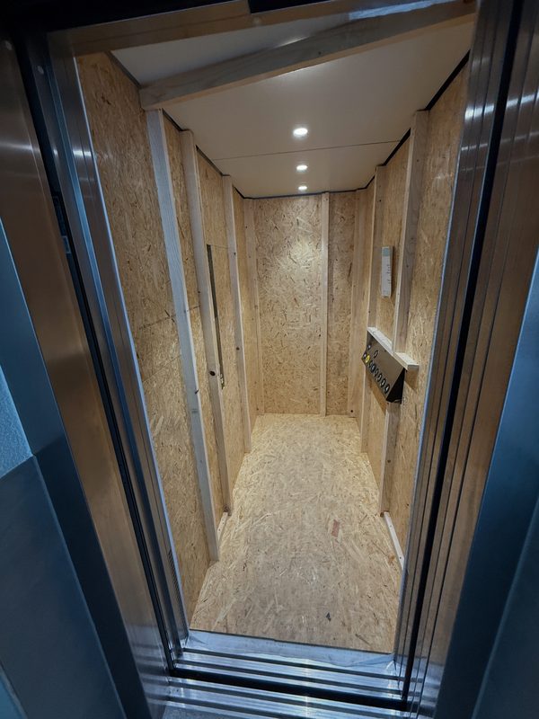 Ein mit Holzplatten ausgeschlagener Aufzug, bereit für den Transport von Möbeln und Kartons