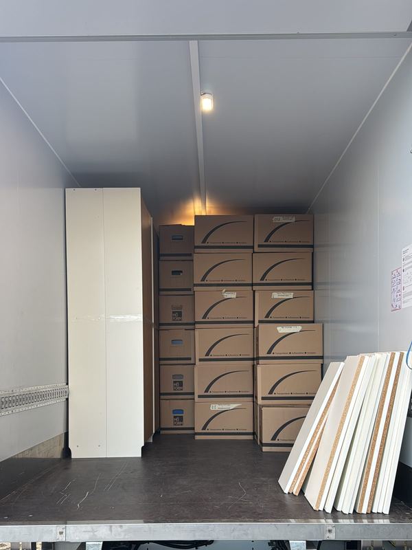 Schrank, Kartons und Holzleisten verladen Gestapelte Kartons, ein weißer Schrank und gebündelte Holzleisten im Laderaum eines Lkw