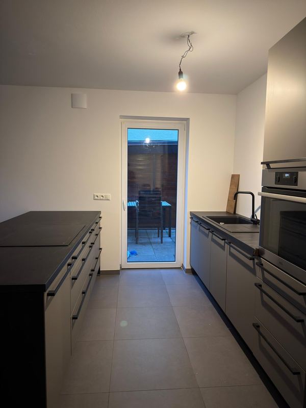 Eine komplett aufgebaute Küche mit Kochinsel und eingesetzten Elektrogeräten in einer Neubauwohnung.