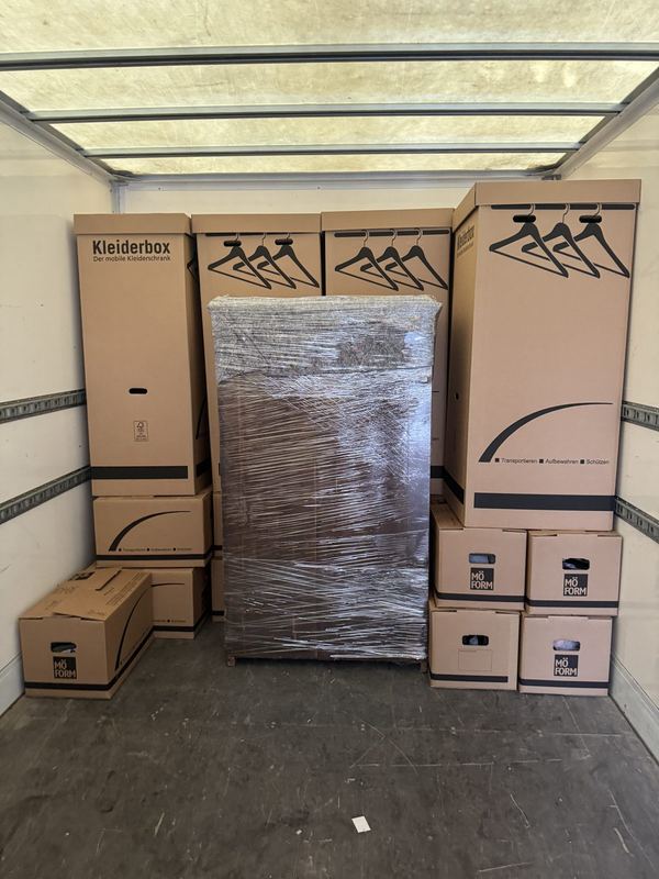 Laderaum mit aufgereihten Kleiderboxen, zwischen ihnen ein Schrank in Folie