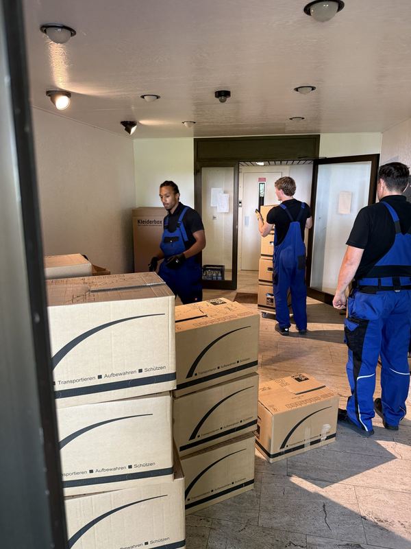 Mitarbeiter reihen Umzugskartons zum Abtransport in einem Flur auf