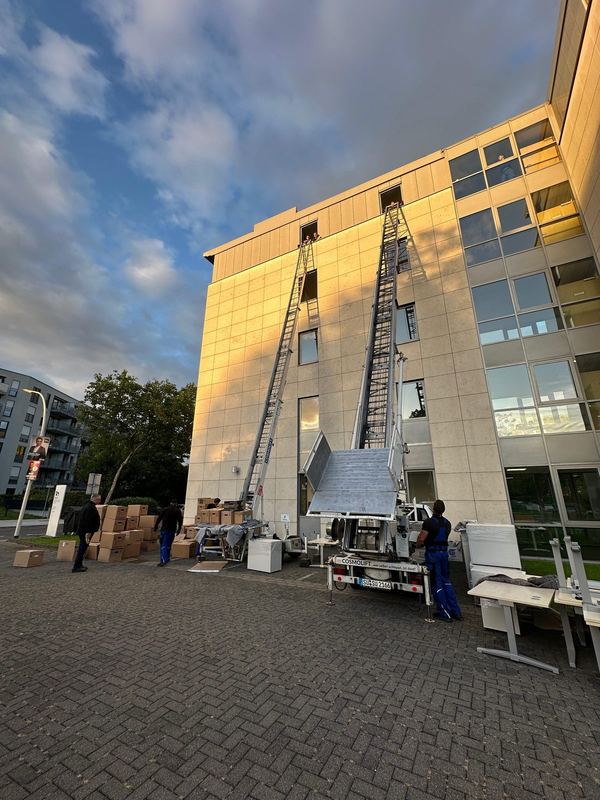 Zwei ausgefahrene Möbellifte nebeneinander vor einem Bürogebäude