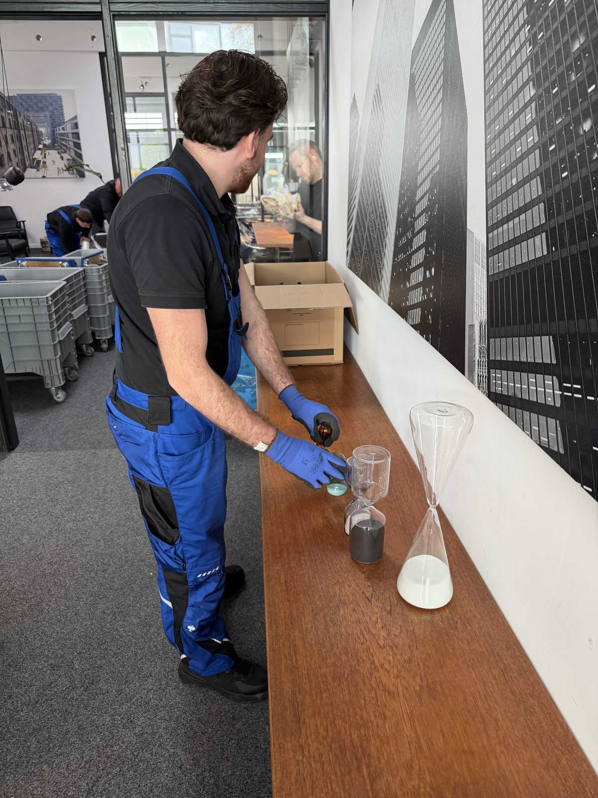 Ein Mitarbeiter mit Handschuhen legt jedes eingewickelte Glas behutsam in den Umzugskarton.