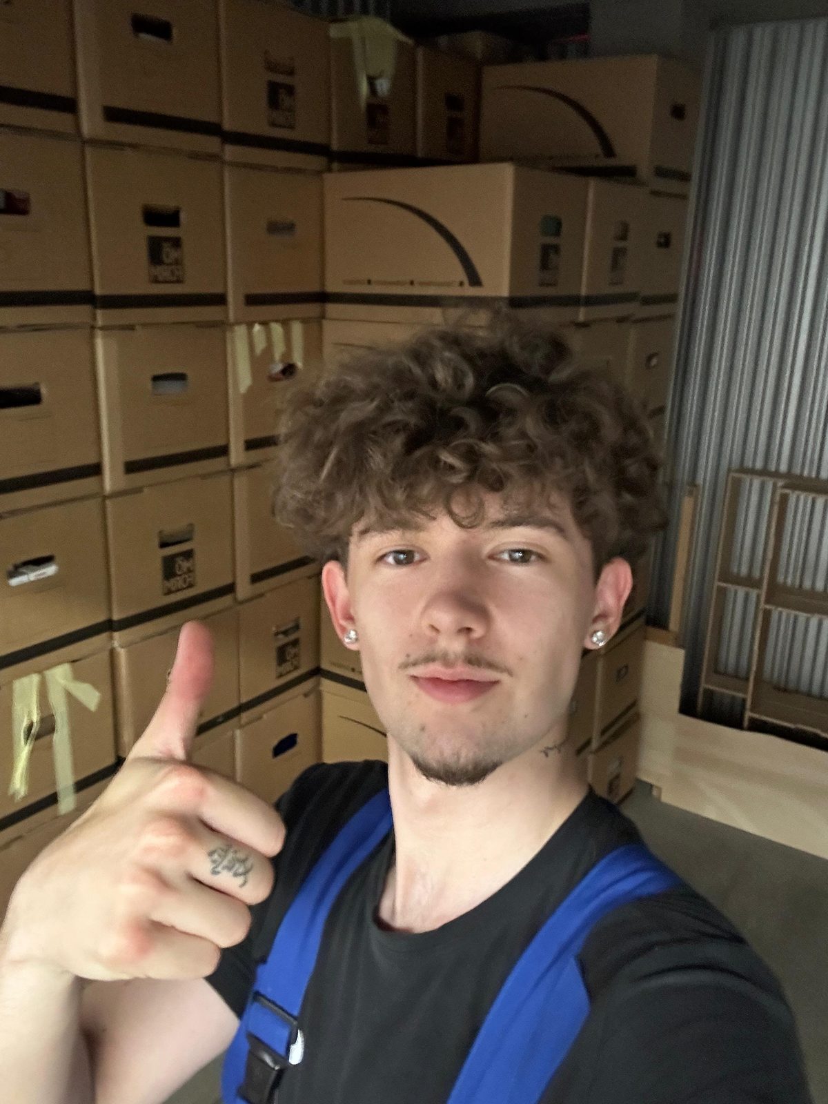 Ein Mitarbeiter steht vor einer Wand aus gepackten und beschrifteten Umzugskartons.