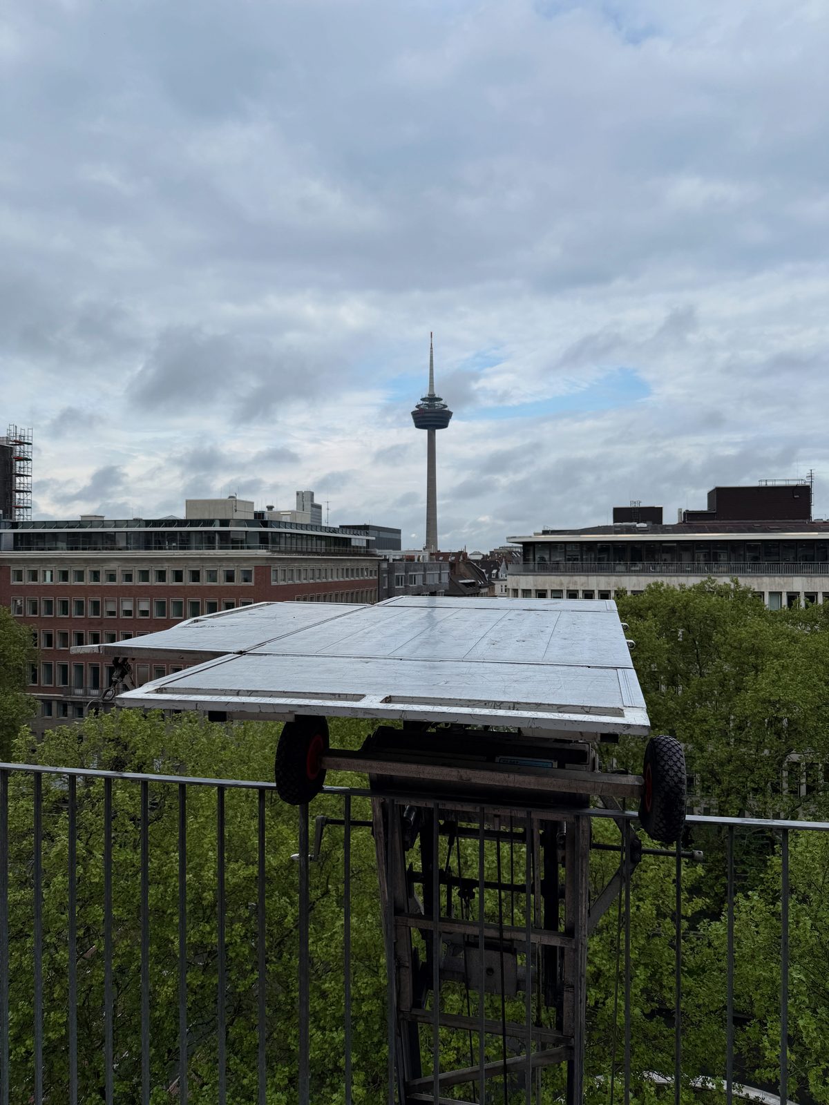 Die Plattform des Möbellifts steht auf Höhe einer oberen Etage, dahinter öffnet sich der Blick über die Stadt.