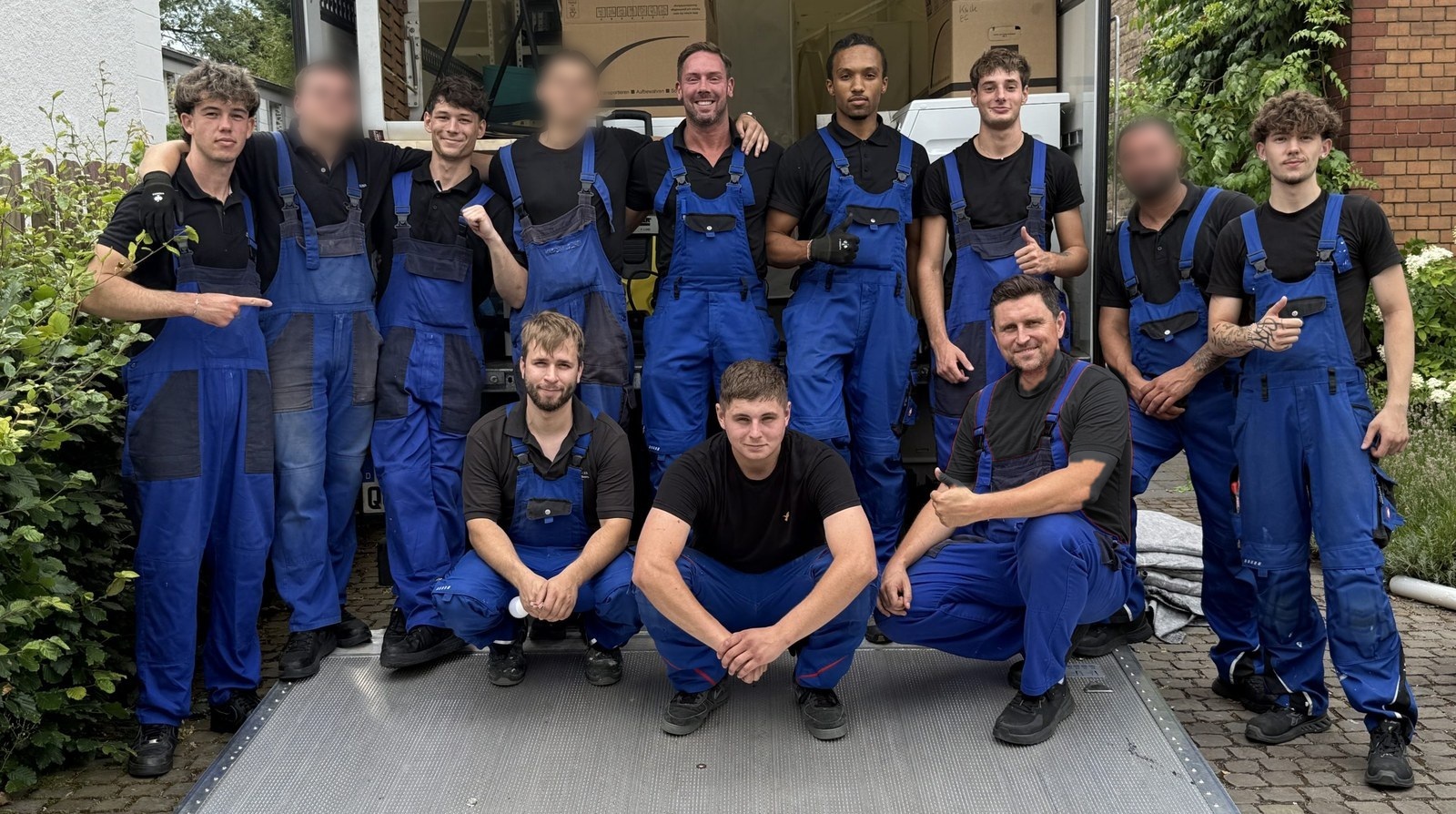 Unser Team steht gemeinsam vor der offenen Ladebordwand des Umzugswagens.