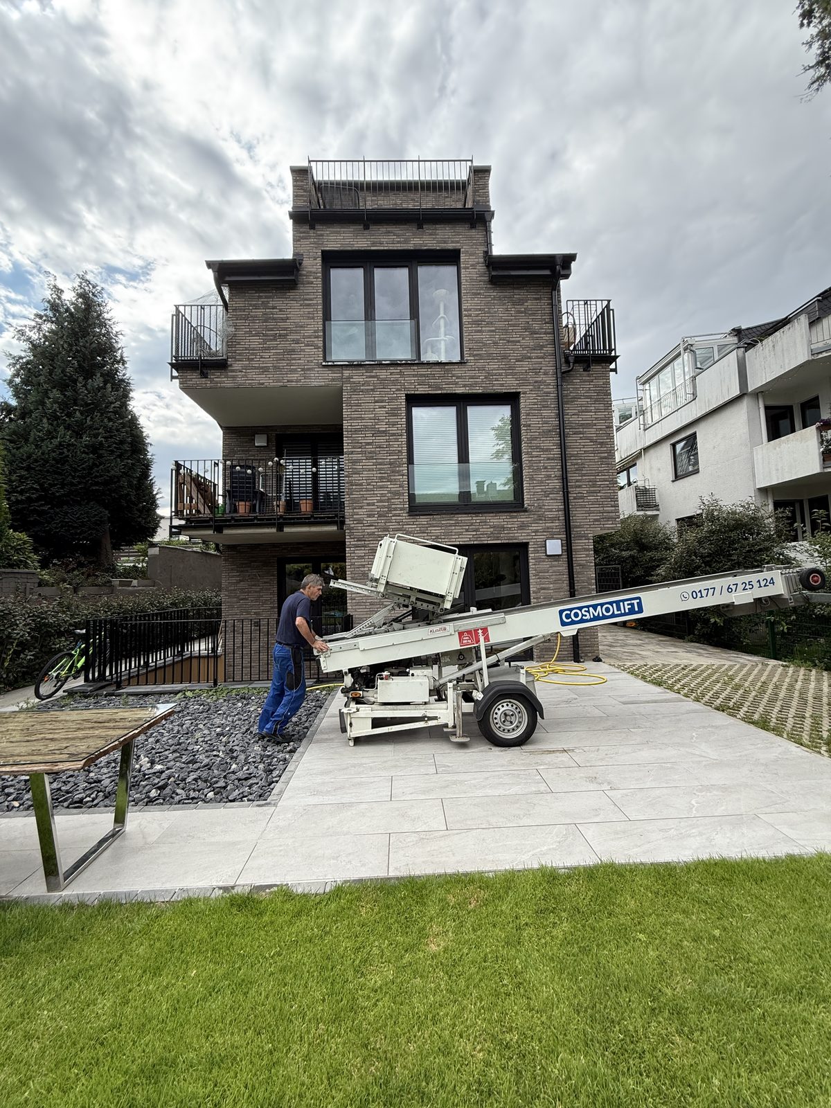 Ein Mitarbeiter richtet den Möbellift auf der Zufahrt eines Wohnhauses ein, bevor der Transport beginnt.